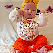 Eden-Rose joined the competition — help win amazing prizes! baby, child, infant, yellow_bow, headband, white_sweatshirt, orange_pants, barefoot, cute, flexing, spooky_season, ghost_design, sitting, blanket, indoors, portrait, expression, clothing, feet, soft_texture