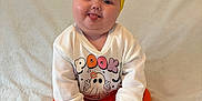 Eden-Rose is registered to the contest to win money with this photo: baby, child, tongue_out, yellow_bow, headband, orange_pants, white_sweater, halloween, witch_hat, garland, sitting, blanket, cute, playful, indoors, smiling, holiday_decor, chubby_cheeks, portrait, happy