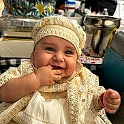 Milton is registered to the contest to win money with this photo: baby, smiling, child, face, hand, clothing, hat, portrait, cute, indoor, people, happy, infant, decorative, fabric, jewelry, person, table, background, blurred