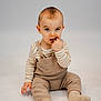Néoh a rejoint le concours — aidez-le/la à gagner de superbes lots ! baby, child, infant, sitting, beige_clothing, striped_shirt, knitwear, cute, playful, fingers_in_mouth, studio_lighting, neutral_background, portrait, small_hands, wide_eyes, floor, footwear, sock, cozy, young