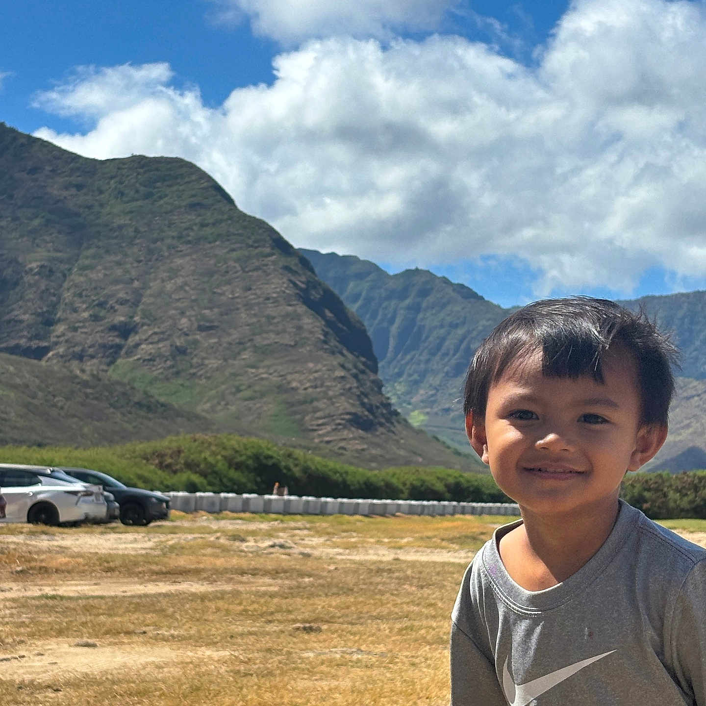 Weston Aydyn is registered to the contest to win money with this photo: boy, car, casual_clothing, child, clouds, daylight, field, grass, happy, landscape, mountains, nature, outdoor, person, portrait, scenic, sky, smile, sunny, young