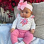 baby, child, pink_clothing, headband, flower, flowers, red_flowers, cushion, sitting, white_socks, outdoor, portrait, cute, infant, soft_texture, hand, baby_girl, fabric, background, nature