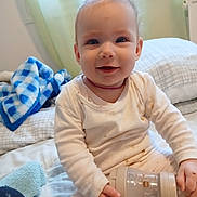 Miya a rejoint le concours — aidez-le/la à gagner de superbes lots ! baby, child, smiling, bottle, bed, blanket, pillow, indoors, white_clothing, hair_tie, cute, happy, sitting, face, person, young_child, cozy, window, soft_light, portrait