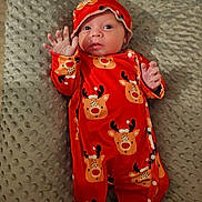 Léandro a rejoint le concours — aidez-le/la à gagner de superbes lots ! baby, child, infant, red_onesie, reindeer_pattern, hat, blanket, textured_blanket, hand_raised, lying_down, cute, holiday_theme, smiling, indoors, portrait, newborn, cozy, clothing, person, face