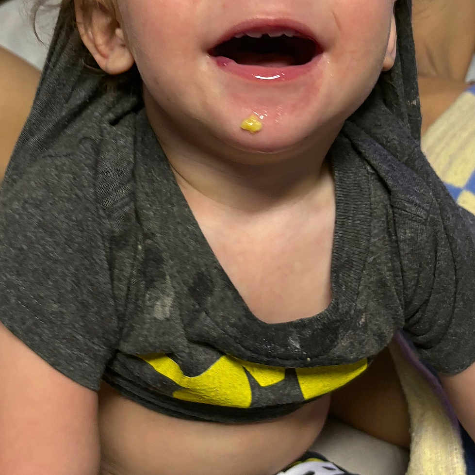 Koda is registered to the contest to win money with this photo: toddler, child, smiling, happy, batman_shirt, messy_face, food_on_chin, short_sleeves, pants, indoor, blanket, seated, person, cute, young_child, casual_clothing, light_skin, hair, cheerful, portrait