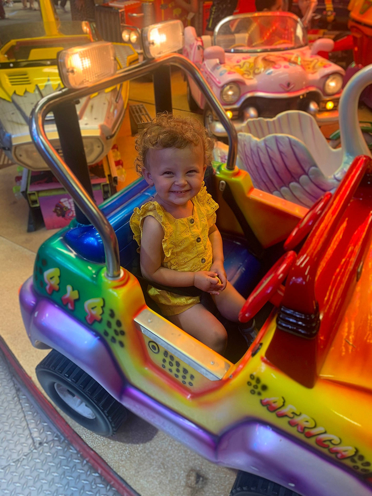 Thea participe au concours pour gagner de l'argent avec cette photo : auto_part, automotive_design, automotive_exterior, automotive_lighting, bumper, car, fun, happy, joy, leisure, mode_of_transport, motor_vehicle, person, public_space, recreation, riding_toy, shorts, smile, tire, toddler