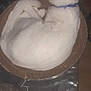 cat, white_cat, blue_collar, cardboard_scratcher, curled_up, tail, tablecloth, patterned, indoor, pet, feline, resting, sleeping, animal, domestic, fur, whiskers, ears, cute, relaxed