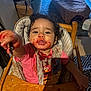 Dalia a rejoint le concours — aidez-le/la à gagner de superbes lots ! toddler, child, high_chair, messy, jam, food, bib, table, wooden, indoor, curly_hair, reaching, smiling, face, hand, clothing, room, carpet, bag, toy