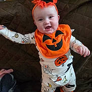 Raelynn joined the competition — help win amazing prizes! baby, child, halloween, pumpkin, bib, smile, orange, white_clothing, spider_web, footwear, cozy, indoor, quilt, cute, festive, headband, happy, person, infant, celebration