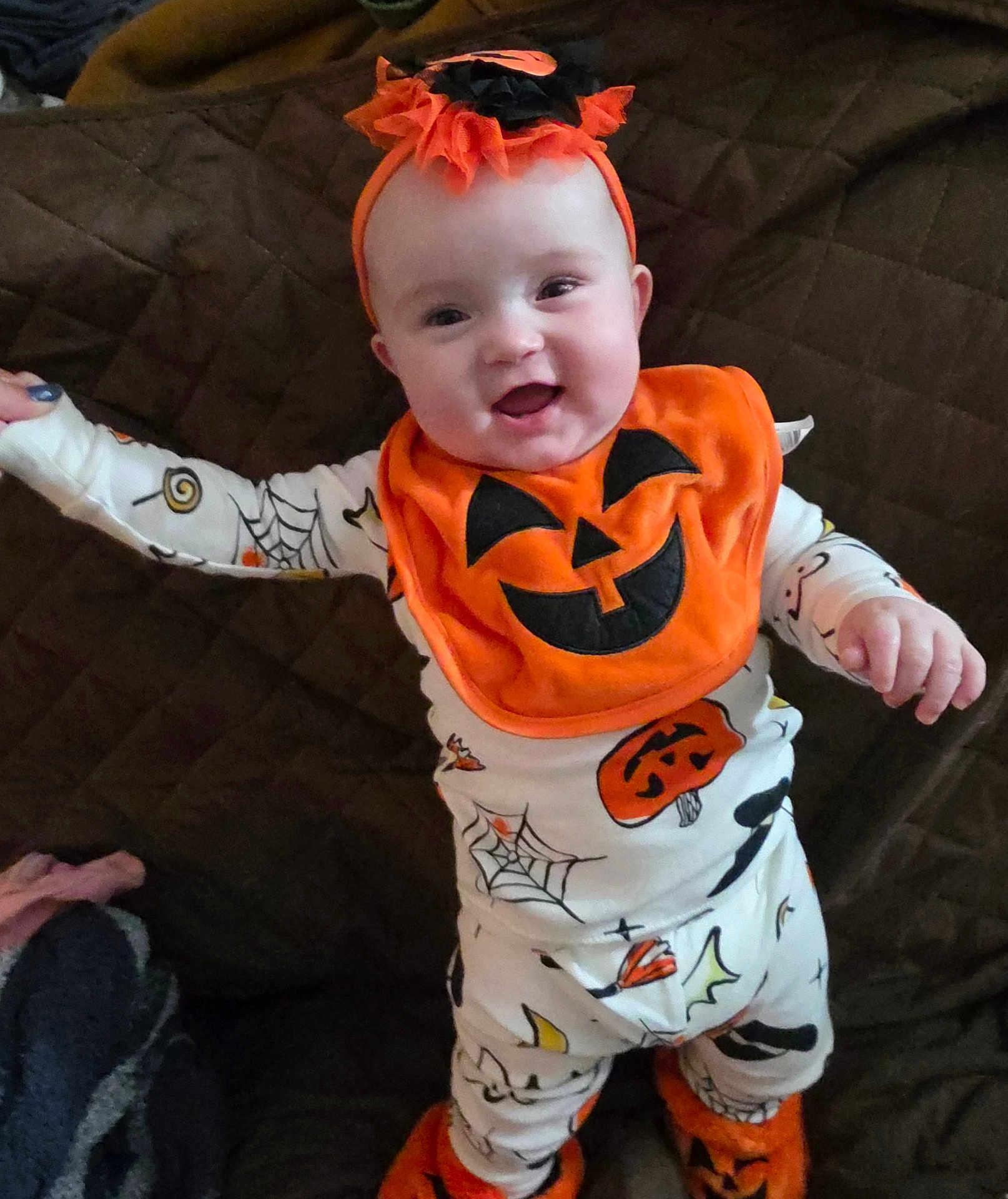 Raelynn joined the competition — help win amazing prizes! baby, child, halloween, pumpkin, bib, smile, orange, white_clothing, spider_web, footwear, cozy, indoor, quilt, cute, festive, headband, happy, person, infant, celebration