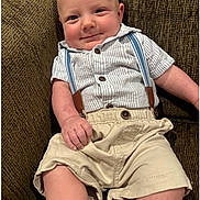 Elliott joined the competition — help win amazing prizes! baby, infant, smile, face, clothing, shirt, suspenders, shorts, couch, furniture, person, skin, hand, leg, seated, cute, happy, indoors, portrait, child