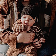 Greyson is registered to the contest to win money with this photo: baby, child, knit_hat, striped_sweater, brown_clothing, fall, autumn, outdoor, family, holding, curious_expression, warm_clothing, bench, nature, pumpkins, casual_wear, portrait, people, hands, seasonal