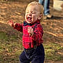 bow_tie, boy, casual_clothing, child, emotion, face, footwear, grass, happy, laughing, nature, outdoor, pants, person, plaid_shirt, shirt, standing, sunlight, suspenders, toddler