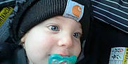 Jasper is registered to the contest to win money with this photo: apparel, baby, blue_eyes, car_seat, child, close_up, cute, expression, face, hat, headwear, indoor, infant, knit_cap, pacifier, portrait, sitting, warm_clothing, warning_label, young_child