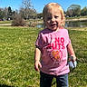 blue_sky, casual_clothing, child, daylight, garden_tool, grass, happy, holding_object, jeans, nature, outdoor, park, pink_shirt, playtime, pond, smiling, sunny, toddler, trees, young_child
