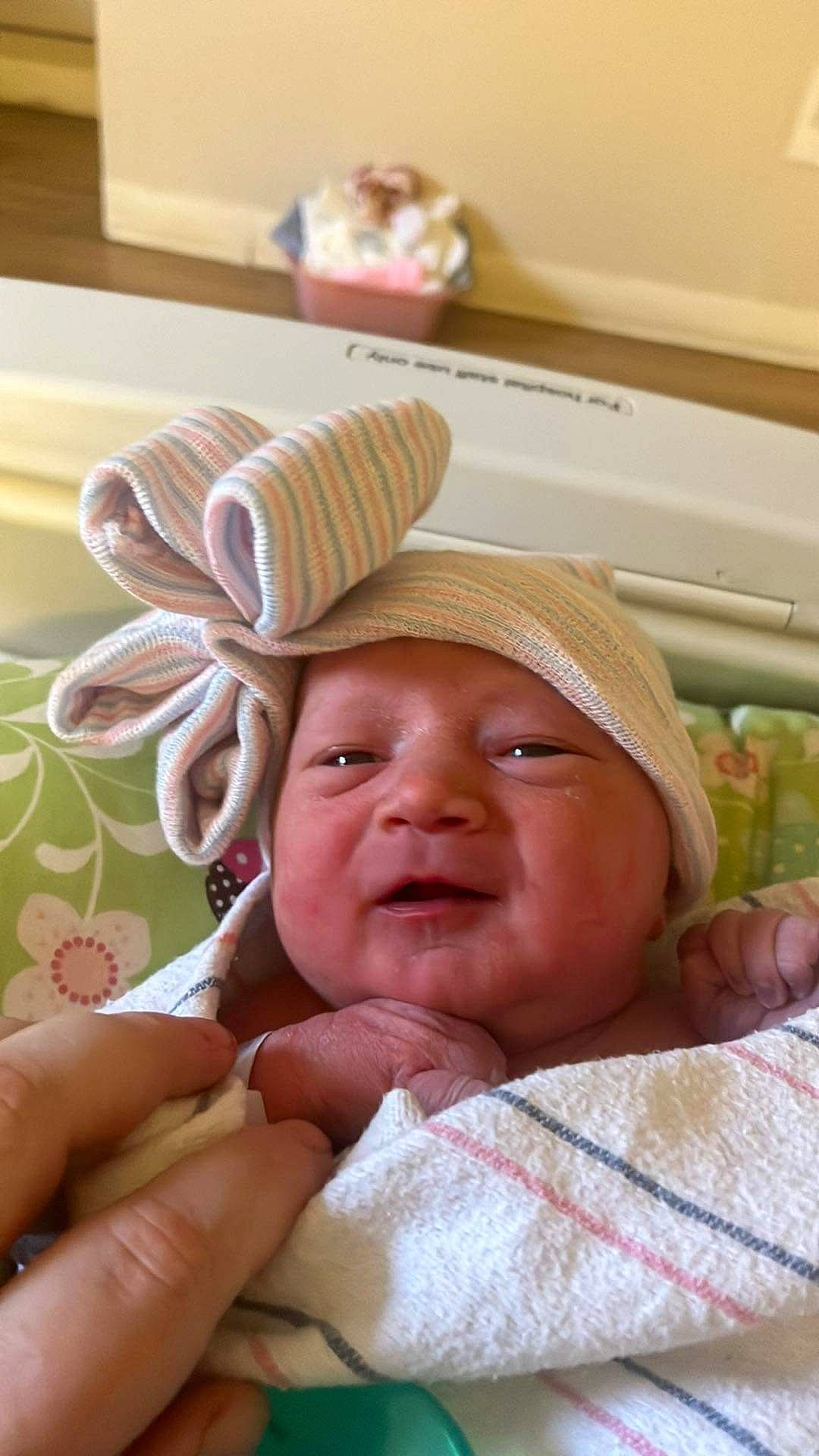 Aurora is registered to the contest to win money with this photo: baby, baby_products, baby_safety, child, comfort, event, face, finger, gesture, happy, hat, headgear, headwear, linens, nail, nose, person, room, skin, smile