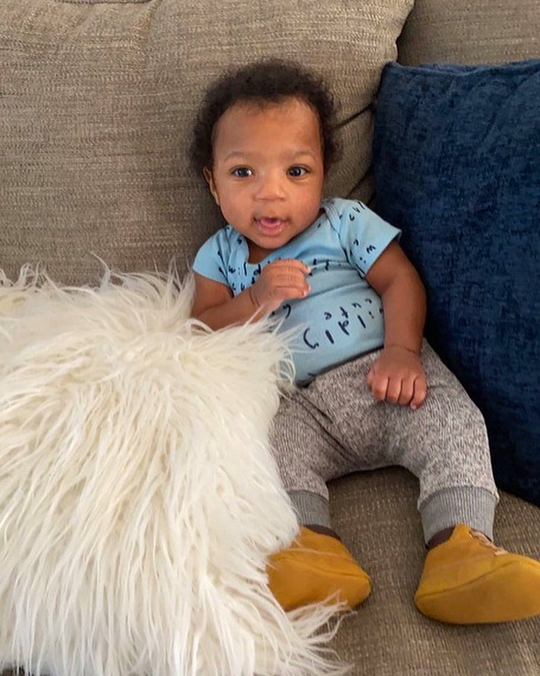 Joseph Richter is registered to the contest to win money with this photo: baby, baby_toddler_clothing, child, comfort, couch, face, finger, flooring, fur, hair, happy, head, human_leg, linens, person, sitting, smile, sock, t_shirt, textile