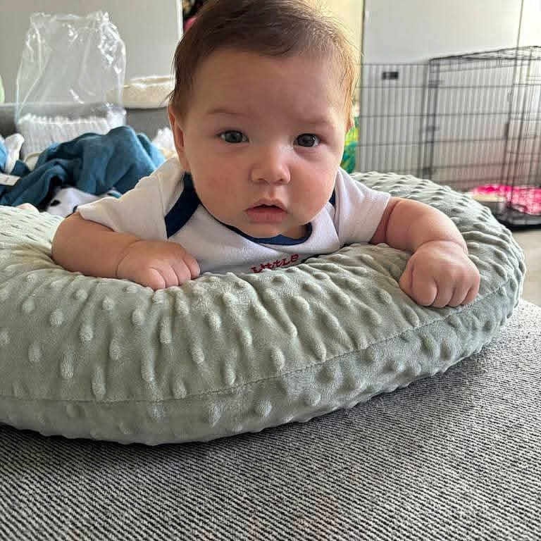 Rene joined the competition — help win amazing prizes! baby, infant, child, portrait, face, eyes, curious, indoor, cushion, pillow, blanket, clothing, sitting, lying_down, home, bedroom, furniture, pet_crate, soft_texture, photography