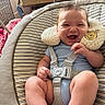 baby, infant, child, smiling, happy, portrait, sitting, bouncer, baby_seat, safety_harness, blue_clothing, plush_toy, bear, striped_fabric, indoor, home, furniture, close_up, playful, photography