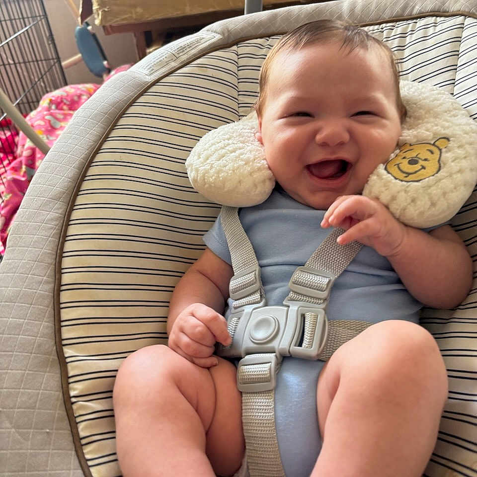 Rene Franco is registered to the contest to win money with this photo: baby, infant, child, smiling, happy, portrait, sitting, bouncer, baby_seat, safety_harness, blue_clothing, plush_toy, bear, striped_fabric, indoor, home, furniture, close_up, playful, photography