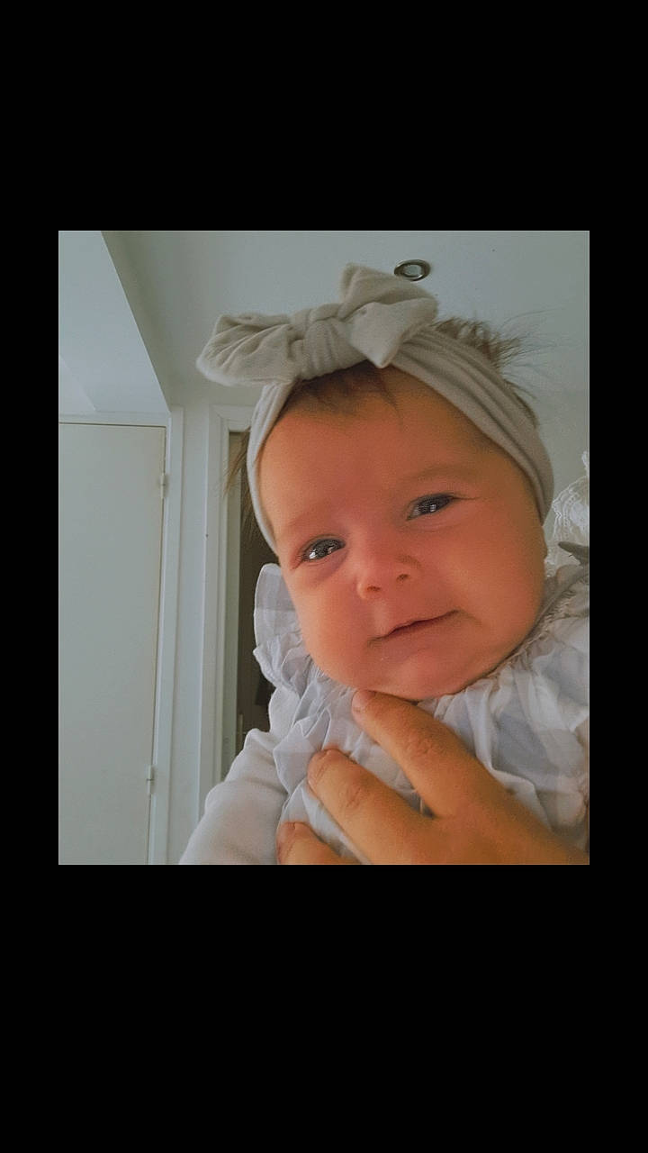 Zoë participe au concours pour gagner de l'argent avec cette photo : baby, baby_toddler_clothing, cheek, ear, eyebrow, eyelash, flash_photography, gesture, happy, headband, headpiece, iris, jaw, lip, nose, person, room, sleeve, smile, toddler