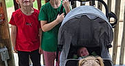 Hazel joined the competition — help win amazing prizes! child, baby, stroller, outdoor, wooden_deck, fence, green_shirt, red_shirt, smiling, happy, dirt_face, casual, family, playful, footwear, pigtails, infant, people, portrait, natural_light