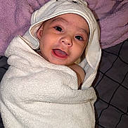 Jesus joined the competition — help win amazing prizes! baby, infant, child, portrait, smiling, tongue, hat, hood, towel, blanket, wrapped, lying_down, bed, bedding, purple, indoors, close_up, face, eyes, cute