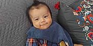 Hélios participe au concours pour gagner de l'argent avec cette photo : baby, child, plaid_shirt, denim_shorts, bib, pacifier, pacifier_clip, couch, gray_couch, pillow, decorative_pillow, smiling, sitting, indoor, cute, infant, happy, person, home, relaxing