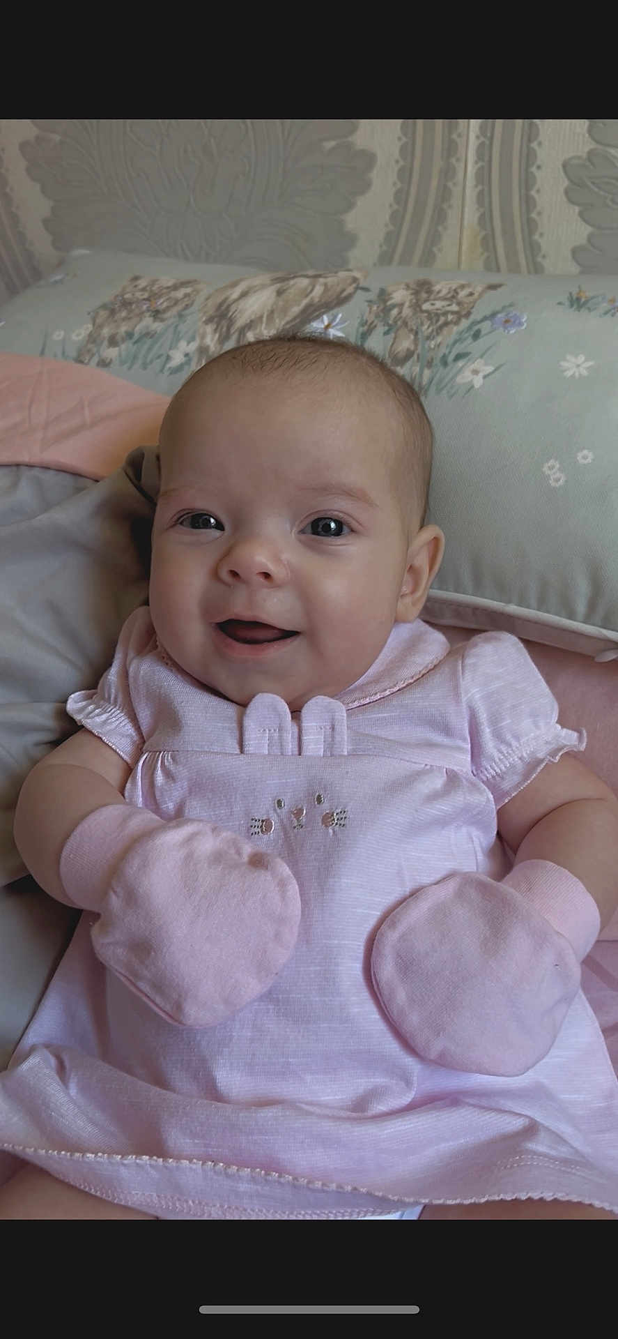 Willow joined the competition — help win amazing prizes! baby, infant, smiling, pink_clothing, mittens, cushion, floral, cute, happy, portrait, indoors, child, soft_lighting, closeup, skin, head, face, eyes, mouth, small_hands