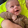 Colton is registered to the contest to win money with this photo: baby, child, smile, happy, face, person, arm, clothing, yellow_shirt, brown_outfit, indoor, infant, closeup, human, skin, cute, joy, expression, holding, portrait