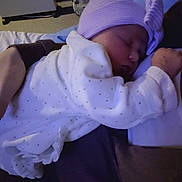 Amélia participe au concours pour gagner de l'argent avec cette photo : arm, baby, bed, blanket, bow, child, cozy, dots, hand, hat, heater, indoor, infant, person, purple, rest, sleeping, soft_lighting, suitcase, white_clothing