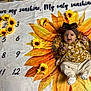 Athena joined the competition — help win amazing prizes! baby, infant, smiling, sunflower, blanket, headband, flower, heart_shape, calendar, yellow, brown, clothing, happy, baby_girl, patterned_clothing, lying_down, indoor, decorative_flowers, cute, portrait