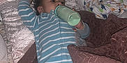 Erick is registered to the contest to win money with this photo: baby, bottle, bed, blanket, pillow, child, sleepwear, striped_clothing, infant, lying_down, indoors, cozy, feeding, soft_texture, resting, person, cute, relaxed, home, sleep