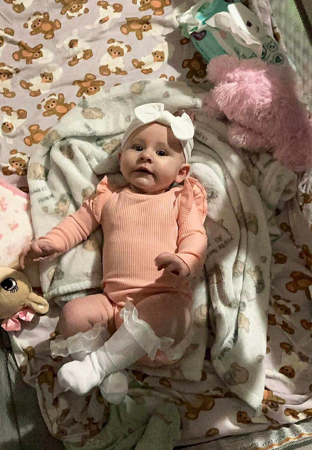 Sarah joined the competition — help win amazing prizes! baby, infant, blanket, bow, pink_clothing, socks, plush_toy, cute, lying_down, teddy_bear_pattern, child, soft_toys, headwear, indoors, cozy, portrait, smiling, young_child, comfortable, nursery