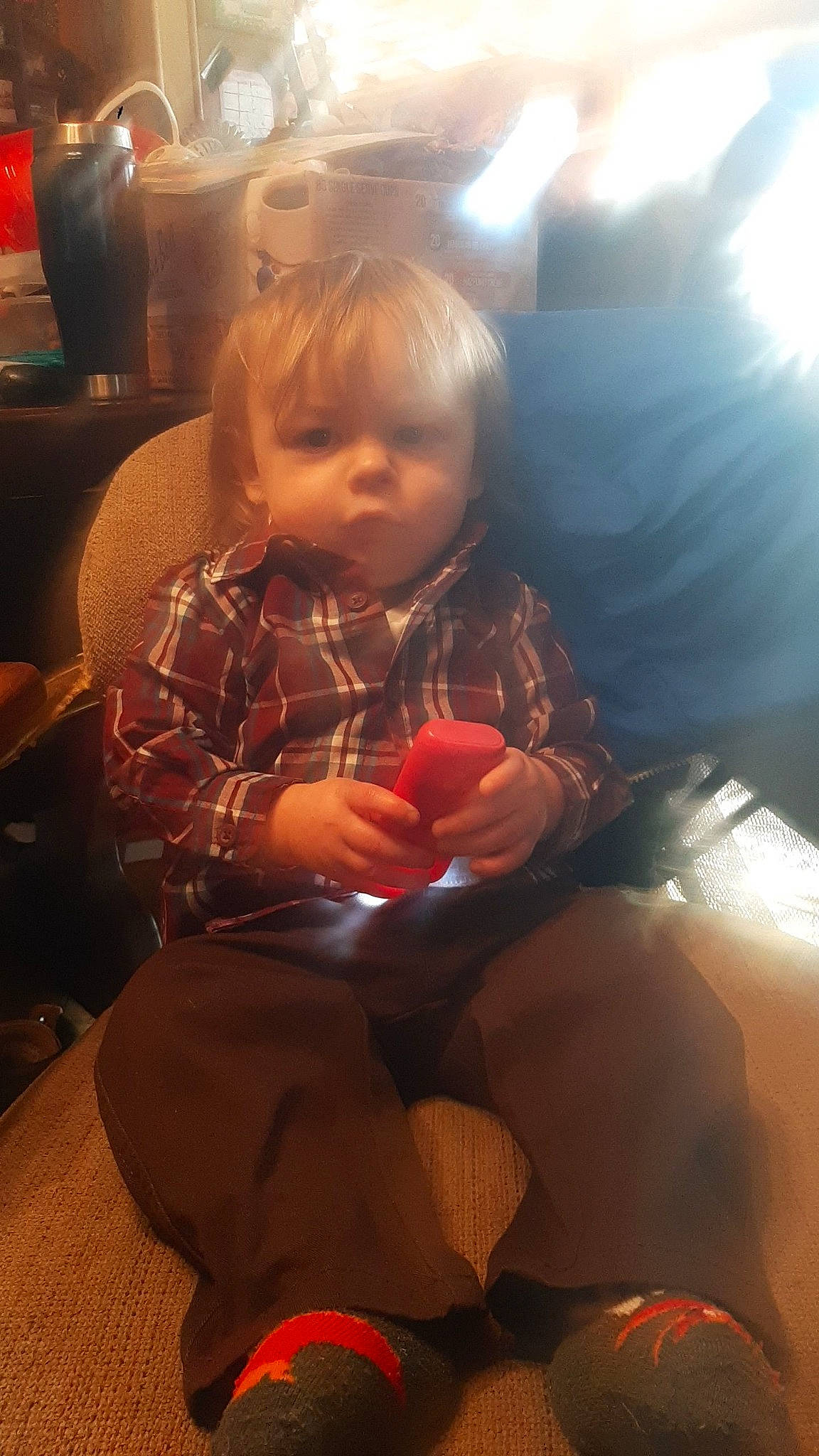 Clayton is registered to the contest to win money with this photo: blond, child, comfort, event, foot, fun, happy, human_leg, knee, lamp, lap, leg, lighting_accessory, mouth, person, room, sitting, thigh, thumb, toddler