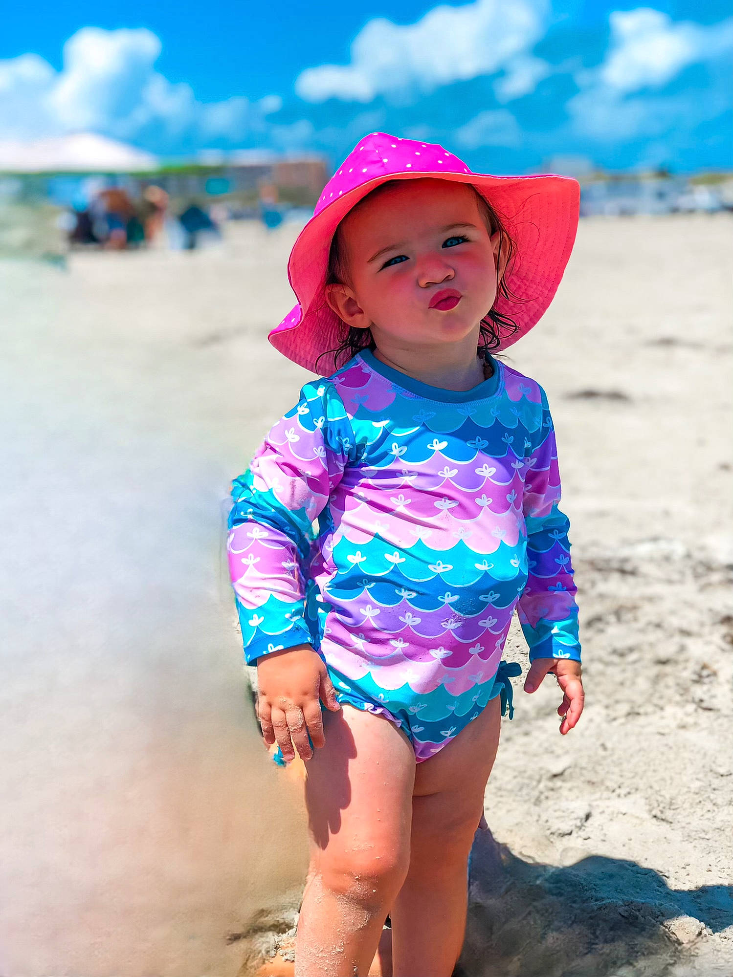 Harlee is registered to the contest to win money with this photo: azure, beach, blue, body_of_water, cloud, cool, eye, happy, hat, headgear, headwear, natural_environment, people_in_nature, people_on_beach, person, pink, skin, sky, sleeve, standing