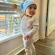 Fernanda joined the competition — help win amazing prizes! toddler, child, window, blinds, hat, pom_pom, knitwear, sneakers, floor, indoor, curious, exploration, standing, light, door, carpet, hand, face, expression, clothing