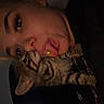 adult, cat, selfie, portrait, indoor, dim_lighting, striped_cat, tabby, pet, animal, person, face, tongue, nose_piercing, black_clothing, chain, closeup, cuddling, funny_pose, home