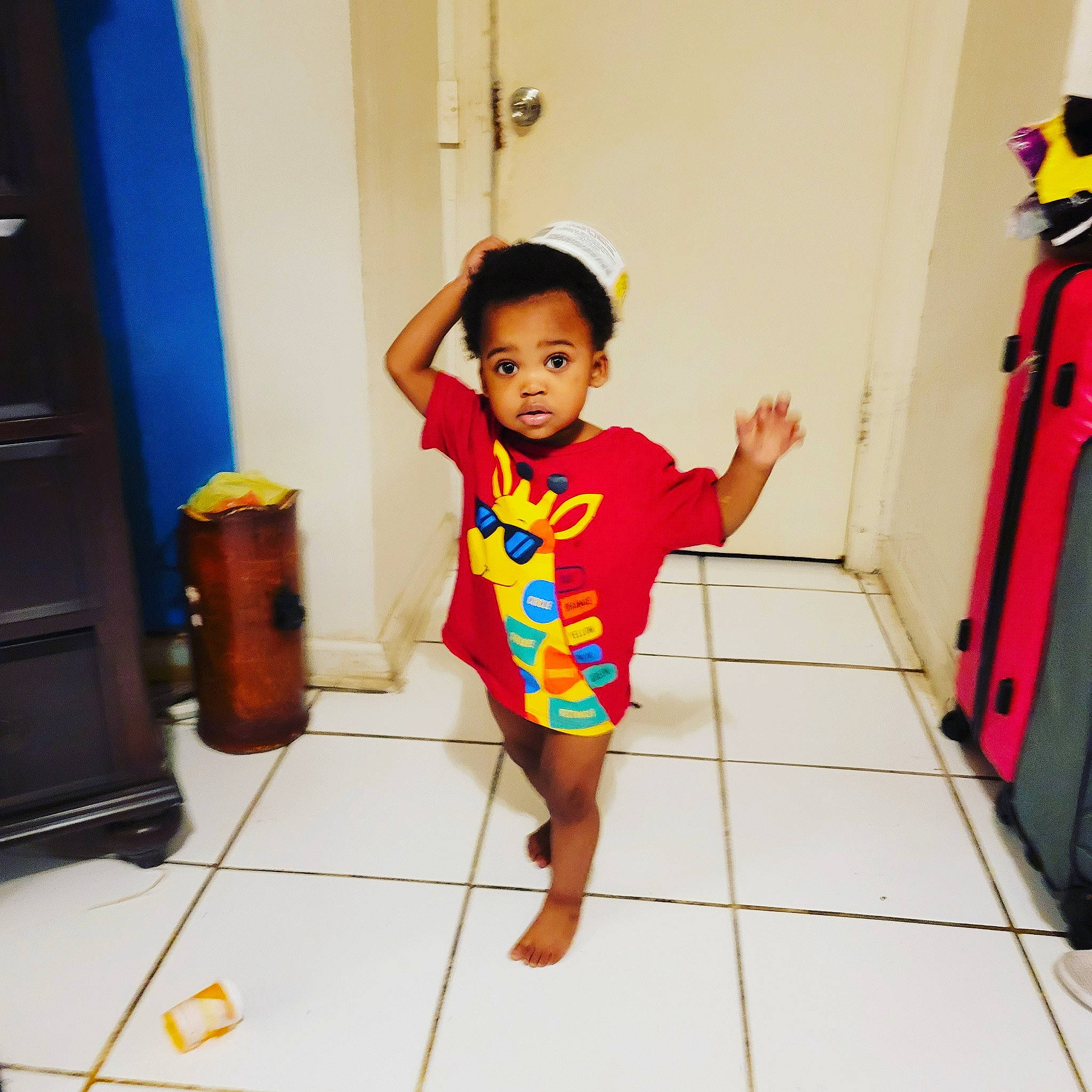 Da' Mori is registered to the contest to win money with this photo: baby, baby_toddler_clothing, child, cleanliness, door, floor, flooring, fun, happy, hardwood, human_leg, orange, person, play, room, sleeve, standing, t_shirt, thigh, toddler