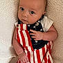 Lakelyn joined the competition — help win amazing prizes! baby, infant, child, person, face, eyes, clothing, red_stripes, white_stripes, blue_stars, blanket, fabric, cute, portrait, laying_down, skin, hand, newborn, soft_texture, curious