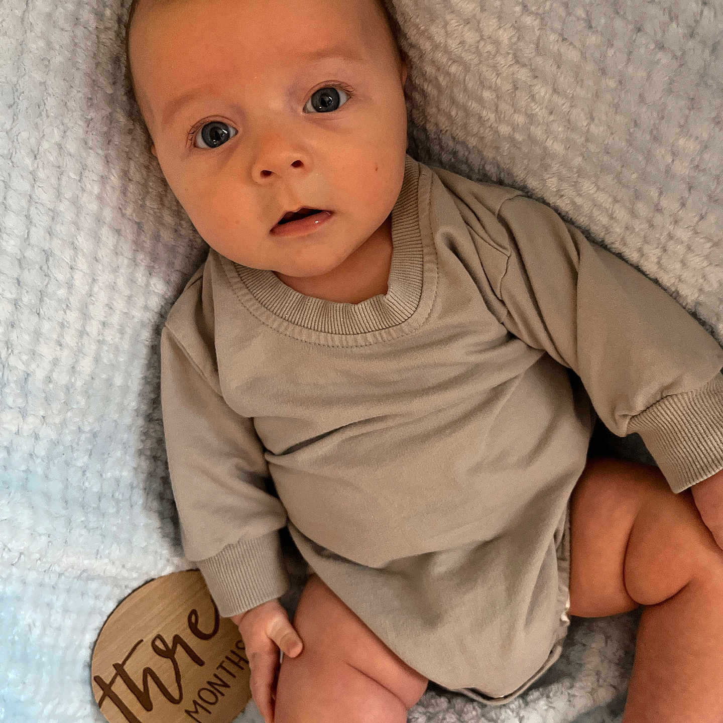 Lakelyn joined the competition — help win amazing prizes! baby, beige_clothing, blanket, child, closeup, cute, expression, foot, hand, indoor, infant, milestone, portrait, sitting, skin, soft_texture, three_months, wide_eyes, wooden_sign, young