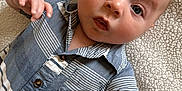 Lakelyn is registered to the contest to win money with this photo: baby, infant, child, blue_eyes, striped_shirt, buttoned_shirt, short_sleeves, lying_down, blanket, soft_texture, curious_expression, hand, face, head, skin, portrait, close_up, person, indoors, casual_clothing