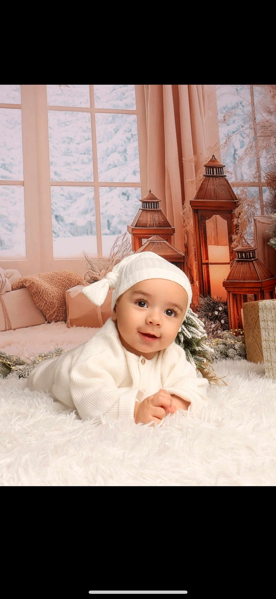 Eyden a rejoint le concours — aidez-le/la à gagner de superbes lots ! baby, infant, white_clothing, hat, smiling, lying_down, fluffy_rug, lanterns, decorations, winter, snow, window, curtains, gift_box, cozy, indoors, holiday, festive, cute, portrait