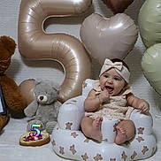 Antonella joined the competition — help win amazing prizes! baby, infant, teddy_bear, balloon, number_5, cake, headband, smile, celebration, inflatable_chair, heart_shaped_balloon, person, cute, child, soft_lighting, white_background, happy, sitting, plush_toy, birthday
