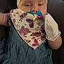 Aliyah is registered to the contest to win money with this photo: baby, child, pacifier, headband, bow, bib, floral_pattern, dress, mitten, indoor, person, face, cute, infant, young_child, apparel, clothing, portrait, sitting, relaxing