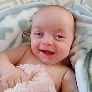 Baylee joined the competition — help win amazing prizes! baby, smile, blanket, cozy, happy, infant, soft, child, face, skin, cute, wrapped, comfort, warm, portrait, lying_down, expression, closeup, indoors, relaxed