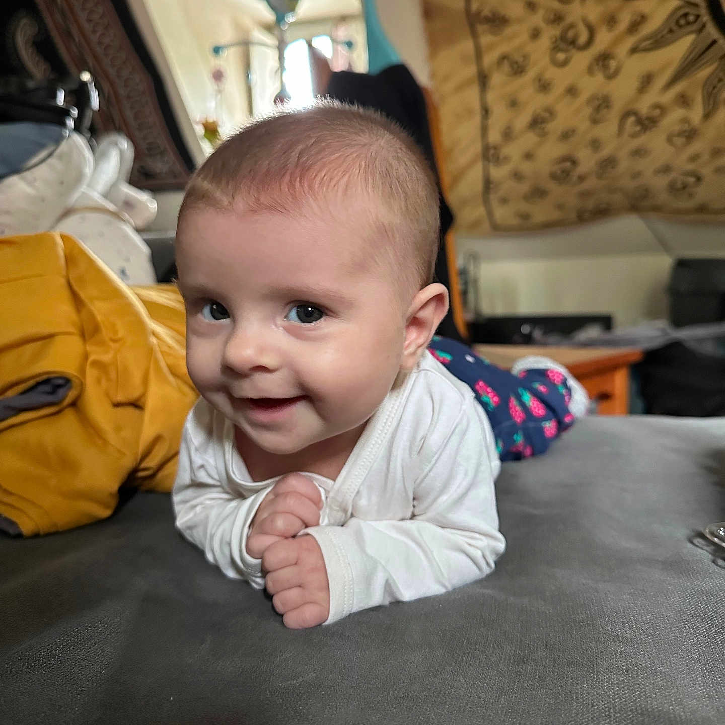 Jade a rejoint le concours — aidez-le/la à gagner de superbes lots ! baby, blanket, child, clothing, cozy, cute, face, furniture, happy, head, home, indoor, infant, person, playful, portrait, resting, smiling, tapestry, tummy