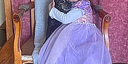 Séréna a rejoint le concours — aidez-le/la à gagner de superbes lots ! child, girl, dog, glasses, purple_dress, princess_dress, hugging, chair, wooden_chair, blanket, indoors, tile_floor, happy, pet, smile, long_hair, footwear, cozy, home, person