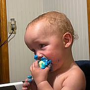 Atlas is registered to the contest to win money with this photo: toddler, child, baby, portrait, eating, dessert, frosting, blue_frosting, cake, messy_face, messy_hands, curly_hair, indoor, high_chair, table, home, close_up, profile, sweet_treat, happy
