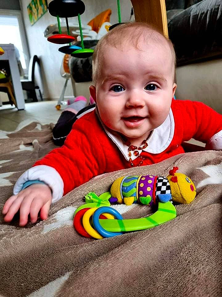 Mia participe au concours pour gagner de l'argent avec cette photo : baby, baby_playing_with_toys, baby_products, baby_toddler_clothing, baby_toys, chair, cheek, child, fun, happy, head, iris, orange, person, play, room, sitting, smile, t_shirt, toddler
